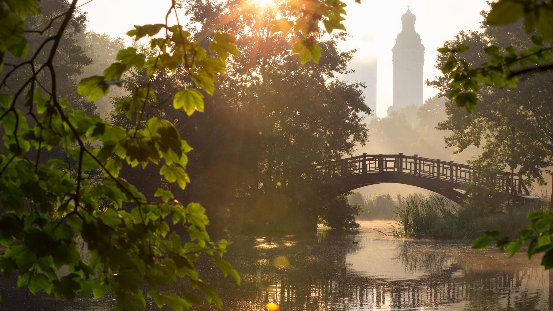 The sun rising above the bridge in Johanna Park with a view of the New City Hall and the City Tower, spring in Leipzig, park