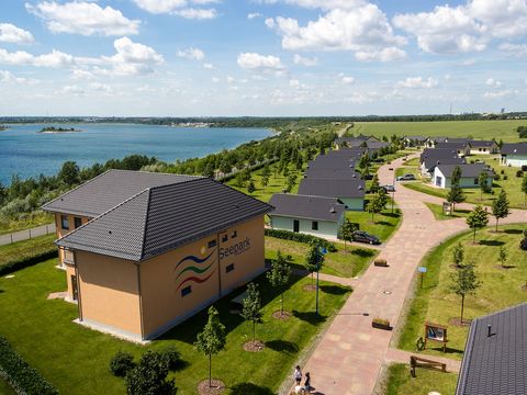 Eine Luftaufnahme des Seeparks Auenhain zeigt die Ferienhäuser, gepflegten Grünflächen und den Markkleeberger See im Hintergrund.