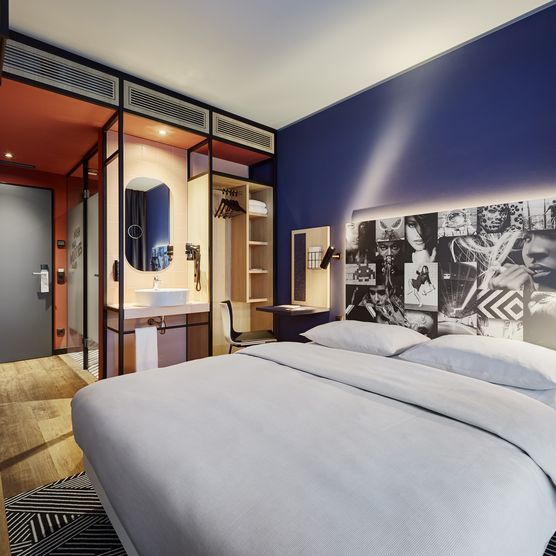 Das Bild zeigt ein geräumiges modern eingerichtetes Schlafzimmer mit blauen Wänden.