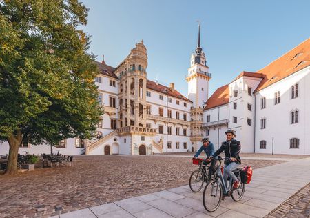 Das Bild zeigt zwei Radfahrer:innen vor dem Schloss Hartenfels.