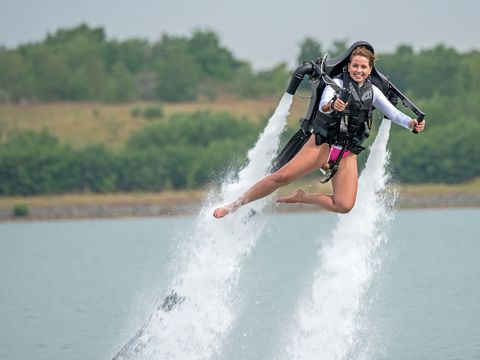 Das Bild zeigt eine Junge Frau über der Wasseroberfläche schwebend mit dem Wasser-Jetpack-Rucksack