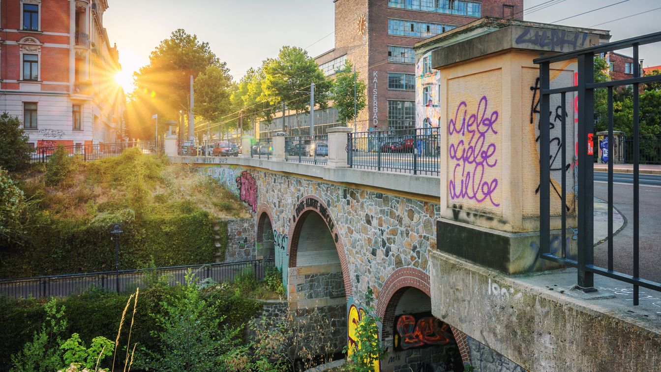 Man blickt auf eine Brücke auf der Karl-Heine-Straße, während die Sonne aufgeht.