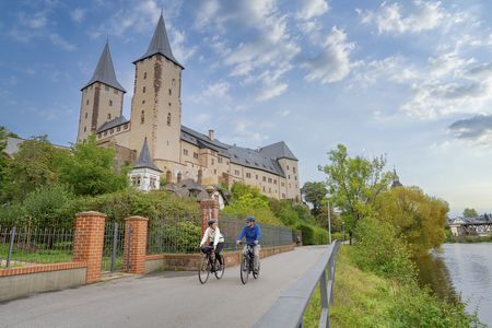 Zwei Erwachsene (Vater und Tochter) fahren Fahrrad vor Schloss Rochlitz an der Mulde, Region Leipzig
