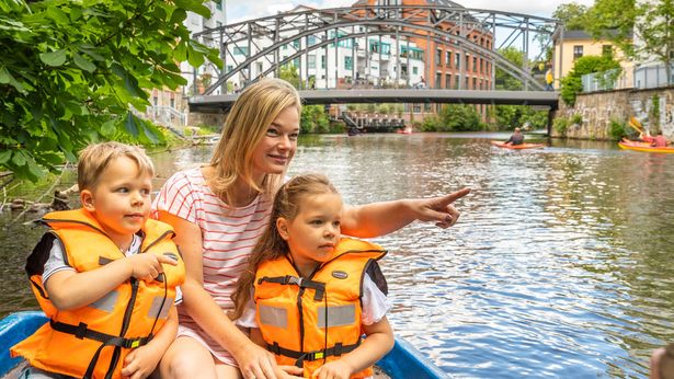 Eine Mutter sitzt mit ihren Kindern in einem Boot, das über die Wasserwege in Leipzig rudert. 