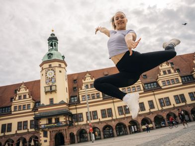 Eine junge Frau turnt vor dem Alten Rathaus Leipzig.