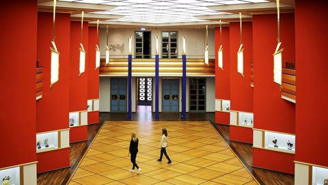 Blick in die Pfeilerhalle mit roten Säulen, Vitrinen und zwei Besuchern