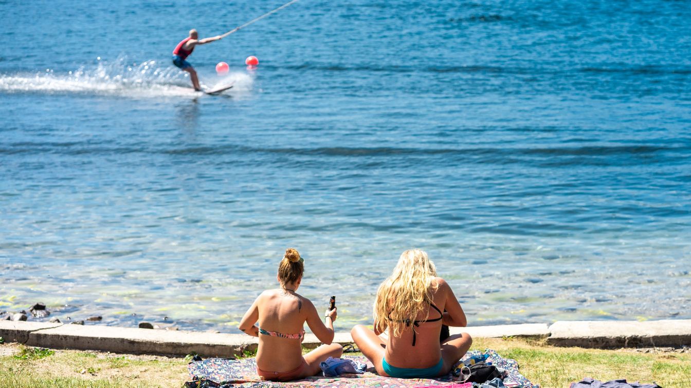Badegäste und Wasserskisportler am Kulkwitzer See bei strahlendem Sonnenschein.